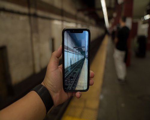 Person holding a smartphone at eye level during an urban train ride commute